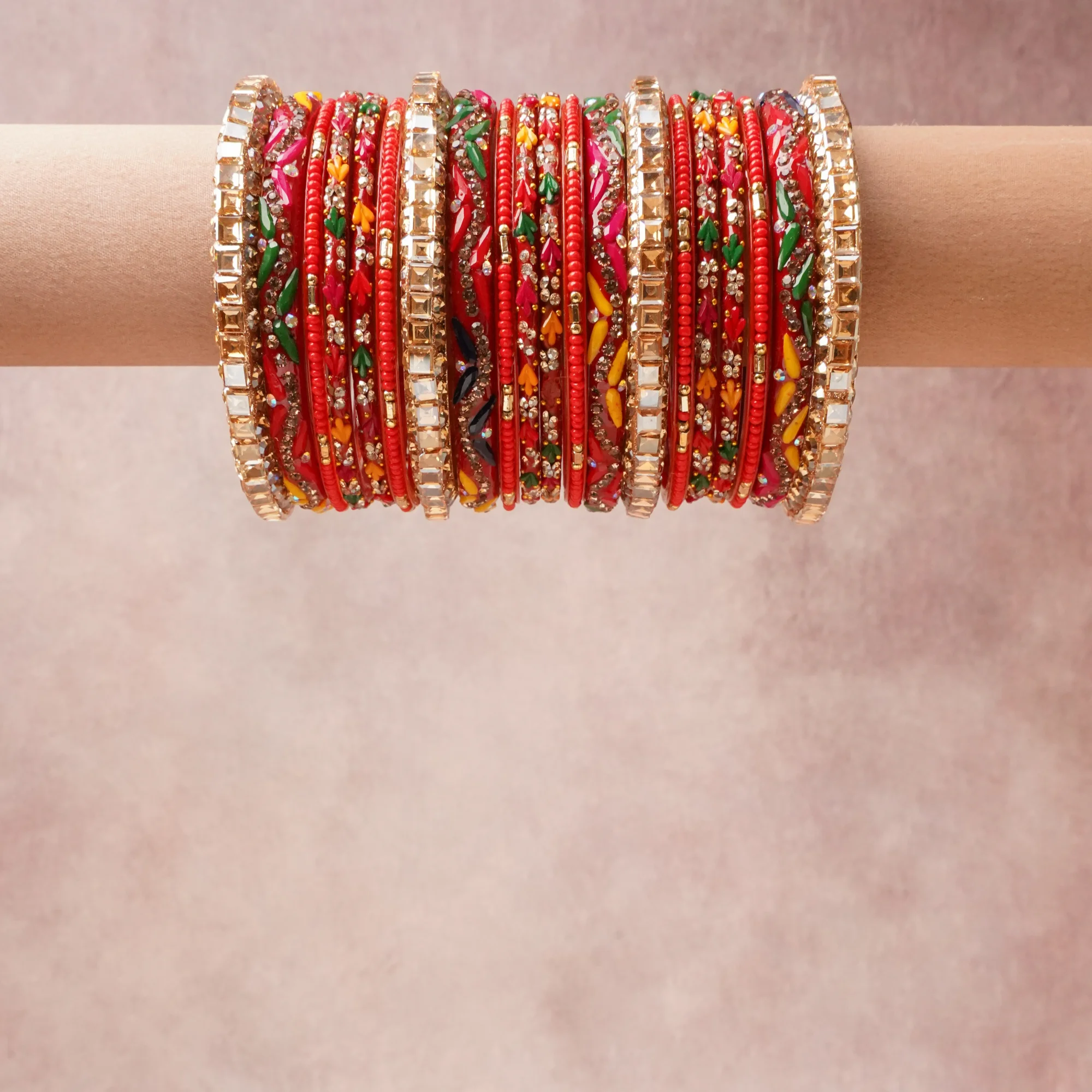 A grounding Crimson Red forms the heart of the set, while touches of Gold, Clear, Emerald Green, Sapphire Blue, Bright Yellow, Fuchsia, White add charm.

A thoughtful composition of Lacquered Bangle Base (Resin/Lac), Gold-Toned Metal, Simulated Diamonds (Cubic Zirconia/Rhinestones), Enamel/Resin Paint, Glass Beads, designed to feel complete without being heavy.
Each element layers seamlessly, creating a look that is refined, wearable and quietly striking.