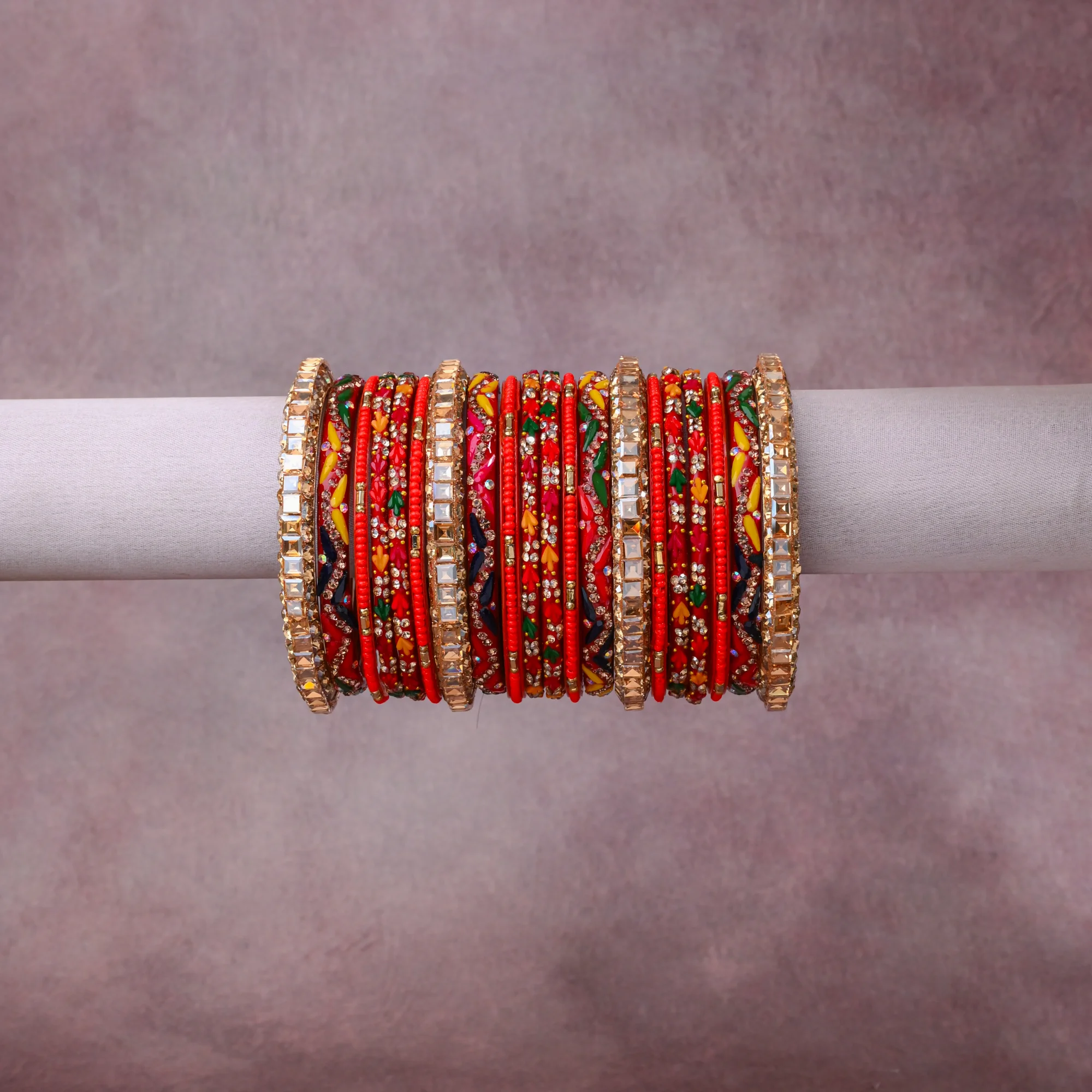 A grounding Crimson Red forms the heart of the set, while touches of Gold, Clear, Emerald Green, Sapphire Blue, Bright Yellow, Fuchsia, White add charm.

A thoughtful composition of Lacquered Bangle Base (Resin/Lac), Gold-Toned Metal, Simulated Diamonds (Cubic Zirconia/Rhinestones), Enamel/Resin Paint, Glass Beads, designed to feel complete without being heavy.
Each element layers seamlessly, creating a look that is refined, wearable and quietly striking.