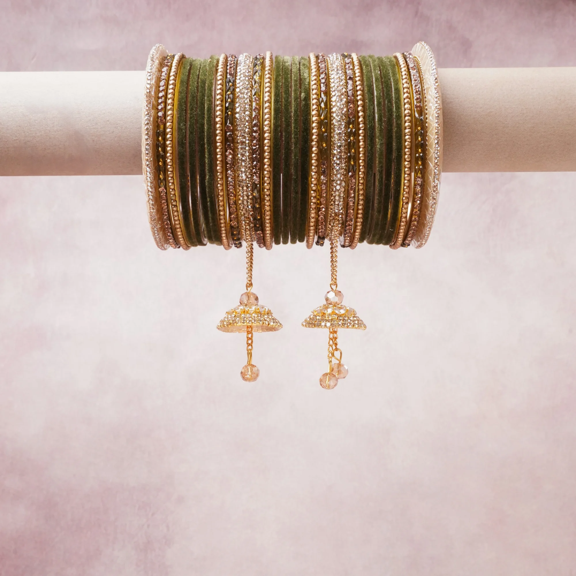 A commanding Olive Green anchors this beautiful set, enriched with accents of Gold, Champagne, Clear that add depth and dimension.

Featuring a striking composition of Velvet Bangles, Gold-Plated Metal, Crystal Stones, this set carries intricate craftsmanship and strong presence. Grand in form, it is created for moments that deserve to be marked.