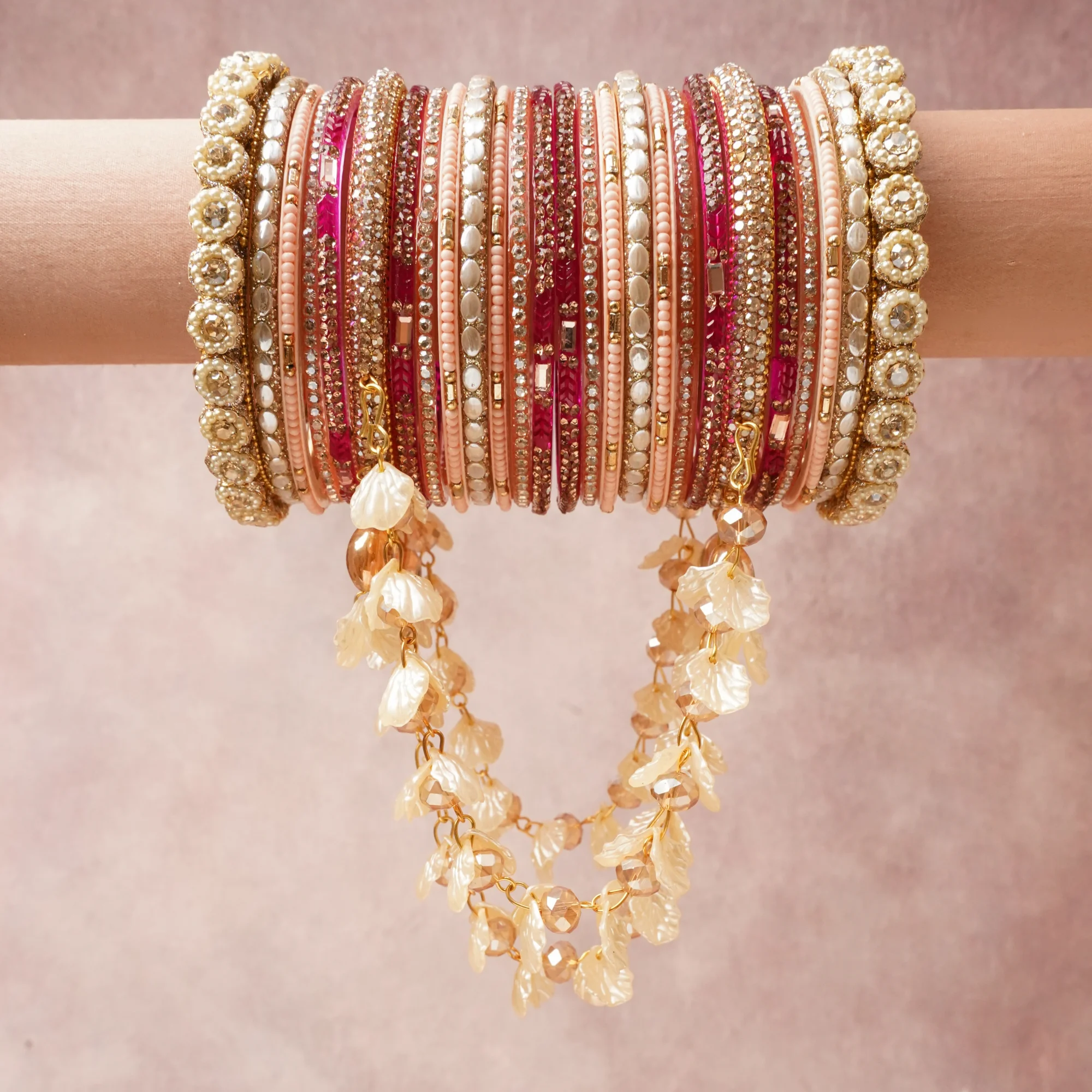 A commanding Blush Pink anchors this beautiful set, enriched with accents of Fuchsia, Gold, Ivory that add depth and dimension.

Featuring a striking composition of Metal Alloy (Gold-toned), Glass (Beads, Crystals), Acrylic (Bangles, Petal Charms), Faux Pearls, Rhinestones, this set carries intricate craftsmanship and strong presence. Grand in form, it is created for moments that deserve to be marked.