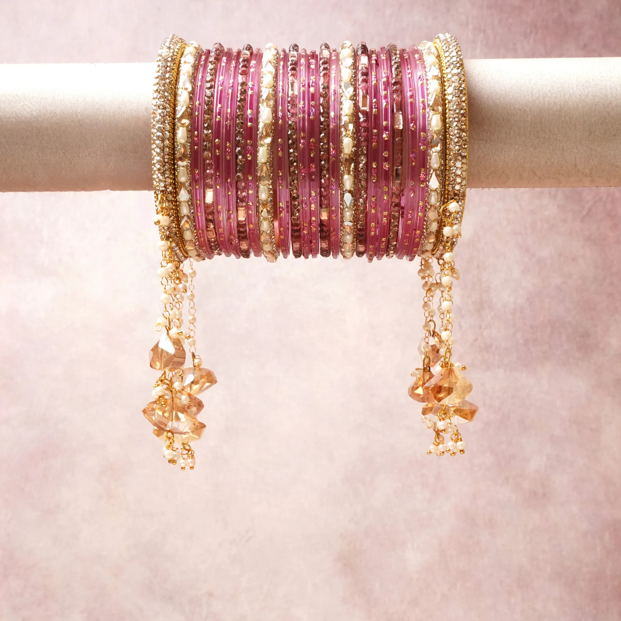 A commanding Pink anchors this beautiful set, enriched with accents of Gold, Ivory, Champagne that add depth and dimension.

Featuring a striking composition of Glass Bangle, Gold Tone Metal, Pearl Beads, Crystal Drops, this set carries intricate craftsmanship and strong presence. Grand in form, it is created for moments that deserve to be marked.