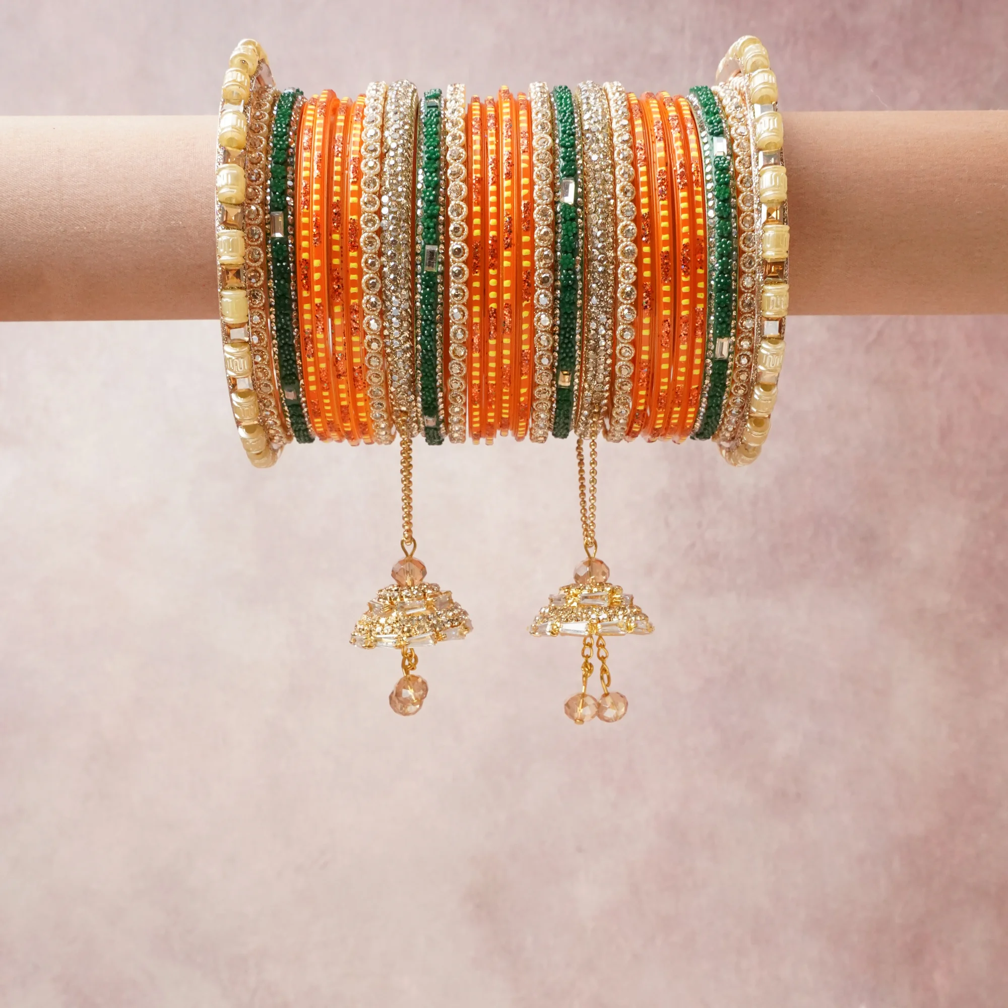 A commanding orange anchors this beautiful set, enriched with accents of gold, emerald green, clear crystal that add depth and dimension.

Featuring a striking composition of glass bangles, rhinestone embellishments, gold-tone metal, this set carries intricate craftsmanship and strong presence. Grand in form, it is created for moments that deserve to be marked.