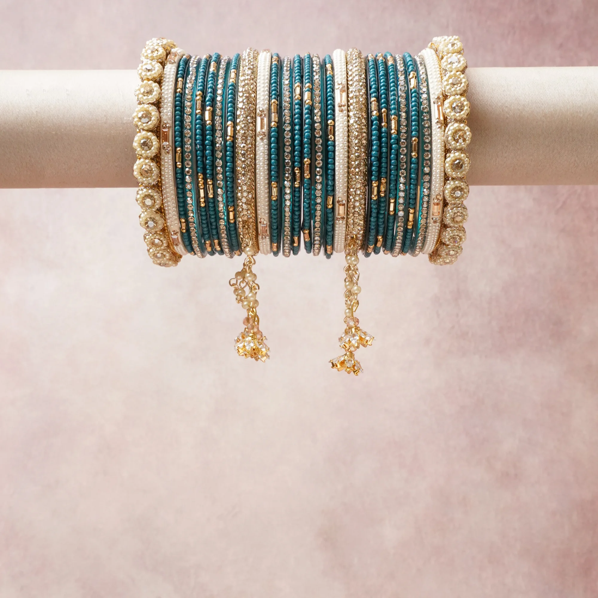 A commanding teal anchors this beautiful set, enriched with accents of gold, ivory, crystal that add depth and dimension.

Featuring a striking composition of beaded metal bangles, this set carries intricate craftsmanship and strong presence. Grand in form, it is created for moments that deserve to be marked.