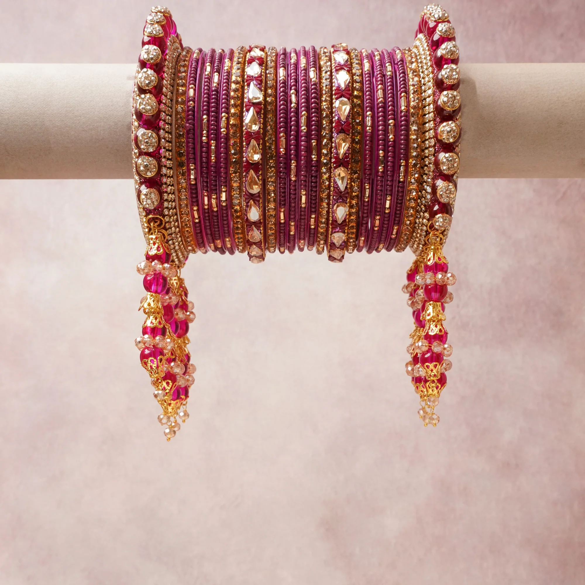 A commanding magenta anchors this beautiful set, enriched with accents of gold, champagne, crystal that add depth and dimension.

Featuring a striking composition of glass bangles, gold-tone metal, rhinestones, this set carries intricate craftsmanship and strong presence. Grand in form, it is created for moments that deserve to be marked.
