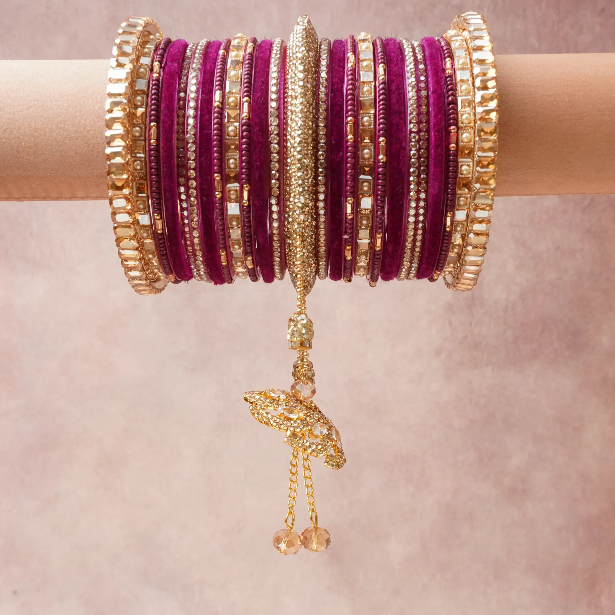 A commanding Magenta anchors this beautiful set, enriched with accents of Gold, Champagne, Rose Pink that add depth and dimension.

Featuring a striking composition of velvet bangles, gold-tone metal, this set carries intricate craftsmanship and strong presence. Grand in form, it is created for moments that deserve to be marked.