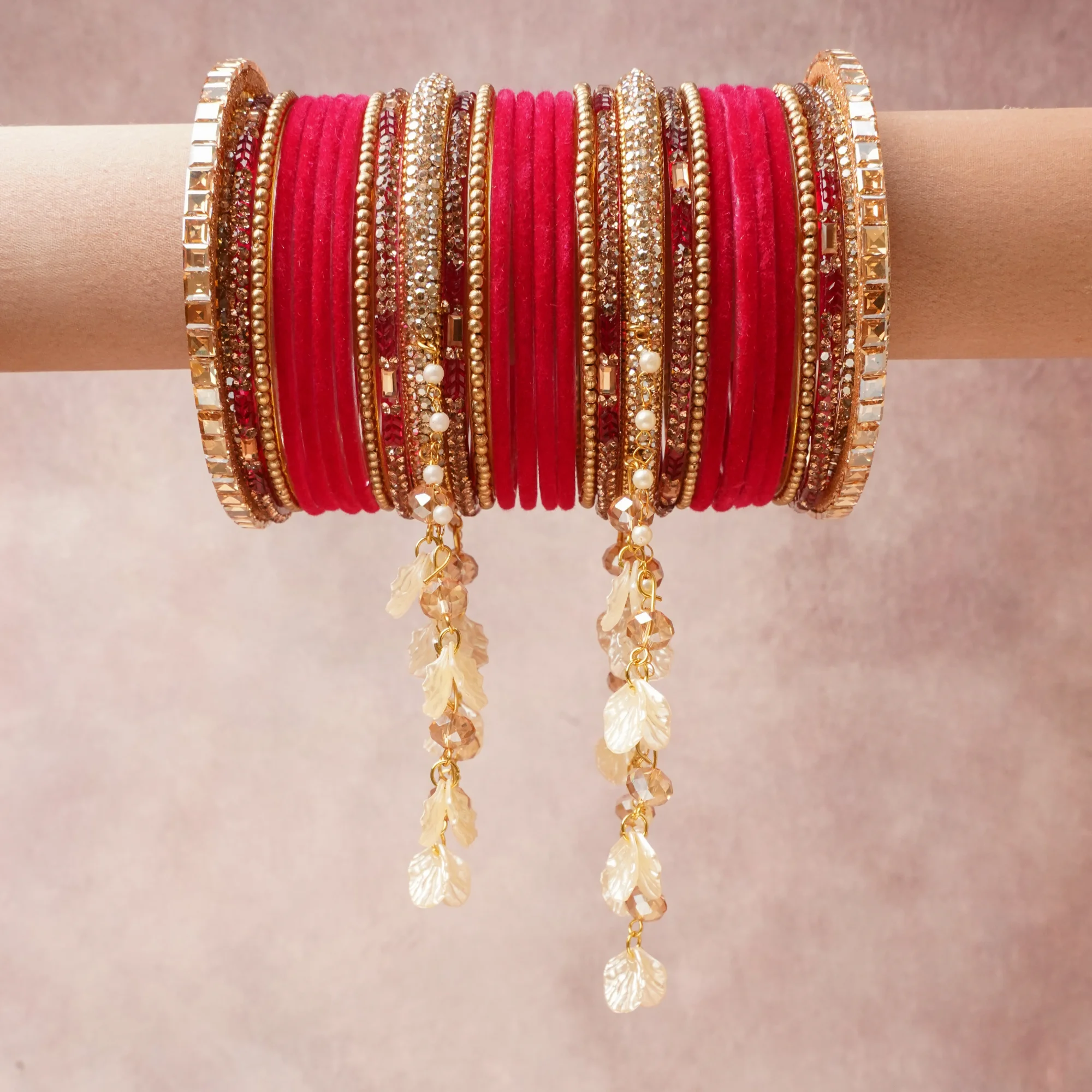 A commanding red anchors this beautiful set, enriched with accents of gold, rose gold, ivory that add depth and dimension.

Featuring a striking composition of glass bangles, gold-tone metal, crystal, pearl, this set carries intricate craftsmanship and strong presence. Grand in form, it is created for moments that deserve to be marked.